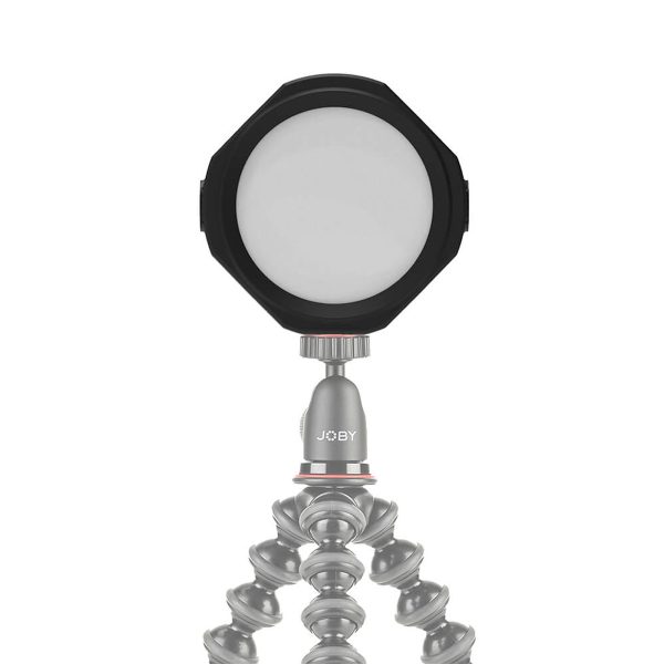 Joby Beamo Studio Background LED-valo on kompakti, pyöreä LED, joka on asennettu joustavaan jalustaan, jossa on segmentoidut, taivutettavat jalat. JOBY-logo näkyy jalustassa valkoista taustaa vasten.