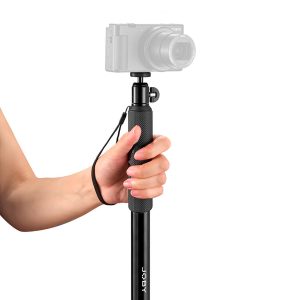 Henkilö, jolla on Joby Compact 2in1 Monopod, jossa on kuvioitu kahva ja rannehihna, ja digitaalinen kamera kiinnitettynä sen päälle.
