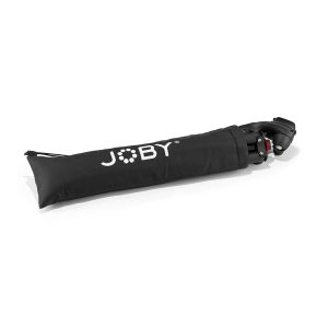 Joby-merkkisessä mustassa kantolaukussa on Joby Compact Action 3K -jalusta, joka on osittain näkyvissä vetoketjullisesta päädystä ulosvedettynä.