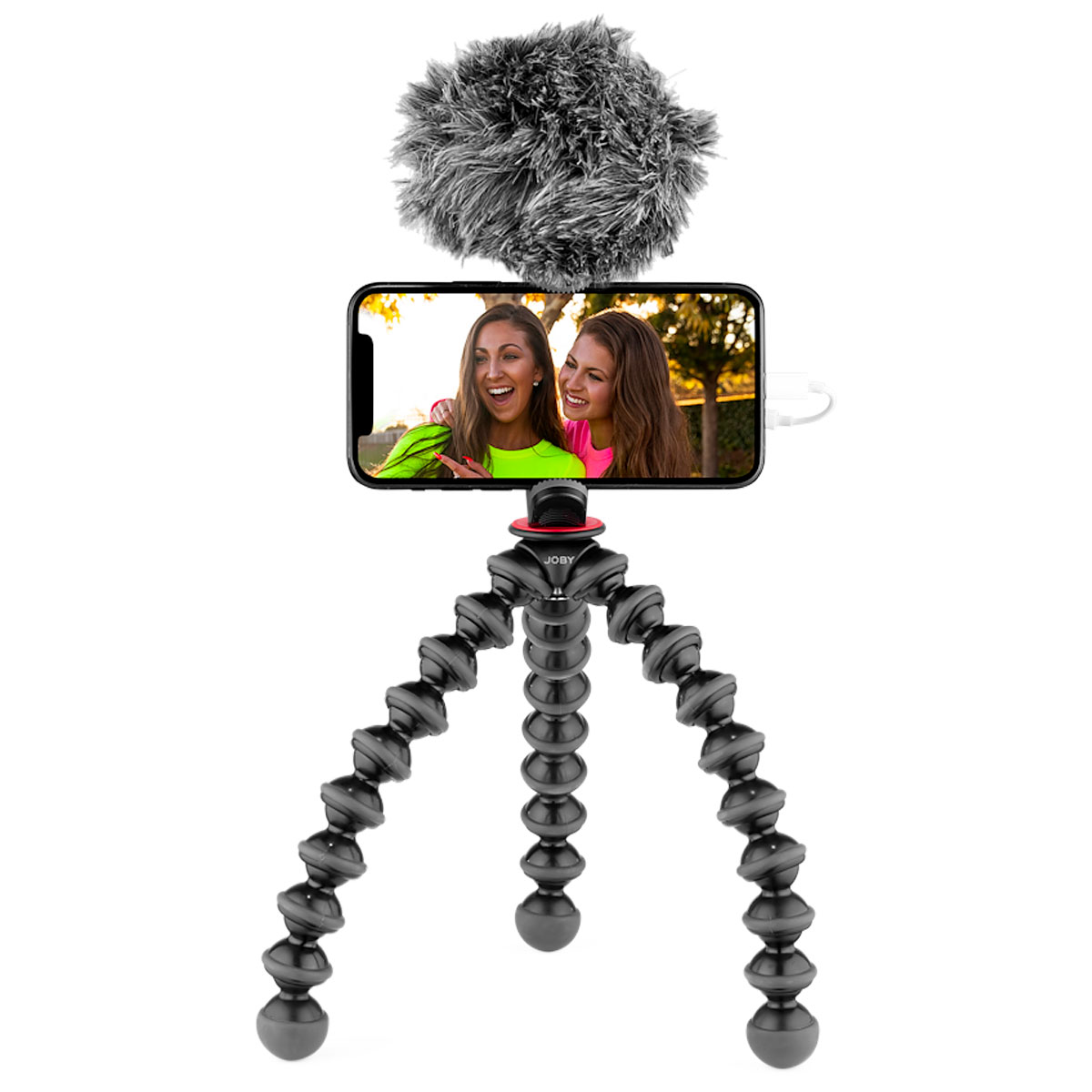 Joby GorillaPod Creator Kit sisältää älypuhelimen, jonka päällä on karvainen mikrofoni. Kaksi hymyilevää naista ottaa selfien puhelimen näytöllä. Jalustan taivutettavat jalat mahdollistavat joustavan ja säädettävän asennon.