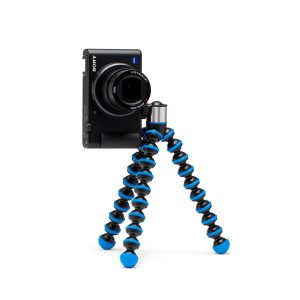 Kompakti Sony-kamera on kiinnitetty Joby GorillaPod Go 500 + GripTight 360 Tripod Kit Blue -jalustaan, jossa on mustat ja siniset segmentoidut jalat ja joka seisoo pystyssä valkoisella taustalla.