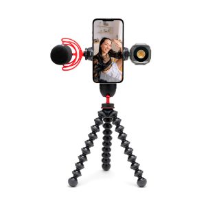 Joby-GripTight-Pro-3-kit-3 A woman smiles and flashes a smartphone screen attached to a Joby GripTight Pro 3 Kit phone stand with a microphone on the left and an LED light on the right on a flexible stand.