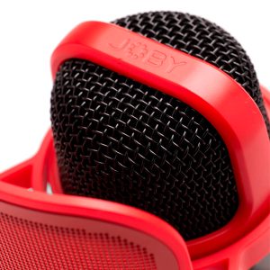 Lähikuva Joby Wavo POD -mikrofoni, jossa on musta muotoilu ja metalliverkkosäleikkö, jota pidetään osittain kirkkaanpunaisessa pidikkeessä, jonka päällä on JOBY-brändinimi.