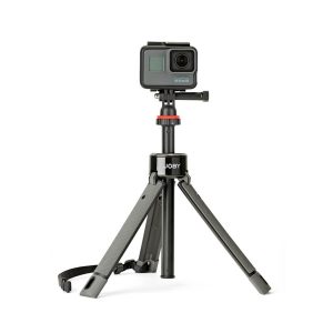 A small black action camera is mounted on the Joby TelePod Pro Kit, a compact tripod with extendable legs and carrying strap, against a white background.