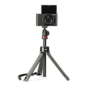 A black Sony digital camera with a swivel screen is mounted on a compact Joby TelePod Pro Kit stand with a carrying strap on one leg, against a white background.