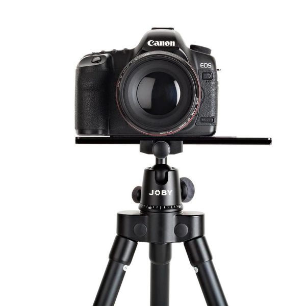 Canon EOS DSLR -kamera, jossa on suuri objektiivi, on kiinnitetty Joby Ultraplate 208 -pikalevyyn valkoista taustaa vasten.