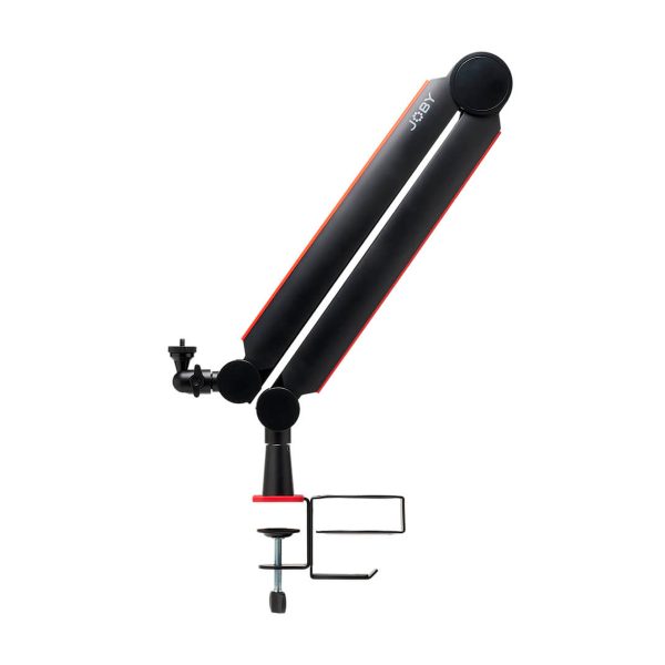 Joby Wavo Boom Arm on mustan ja punaisen värinen säädettävä mikrofonivarsijalusta, jossa on pöytäkiinnike, kuvassa sivukuva valkoista taustaa vasten.