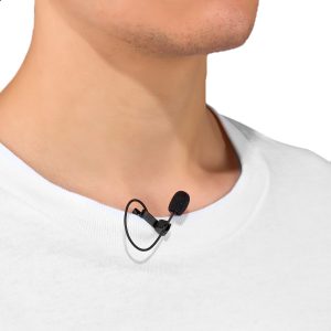 Lähikuva henkilöstä, jolla on valkoinen paita ja Joby Wavo Lav PRO Mikrofoni, pieni musta lavalier-mikrofoni, joka on kiinnitetty kauluksen lähelle kaulaa.
