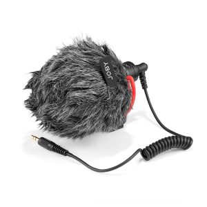 Joby Wavo Mobile - Mikrofoni on kompakti mikrofoni, jossa on karvainen tuulisuojalappu, jossa näkyy JOBY-brändi, kierretty punainen ja musta kaapeli sekä 3,5 mm:n ääniliitäntä valkoisella pohjalla.