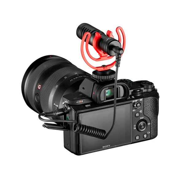 Musta Sony-digitaalikamera, jossa on suuri objektiivi ja jonka päälle on asennettu Joby Wavo Mobile - Mikrofoni kierrekaapelilla. Mikrofonissa on punainen iskukiinnike, ja kamera näkyy takaa.