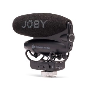 Musta Joby Wavo Pro - Mikrofoni, jossa on vaahtomuovinen tuulisuoja, "Active Noise Reduction" kyljessä, asennettu pieneen säädettävään jalustaan, jossa on ohjauskytkimet ja valitsin.