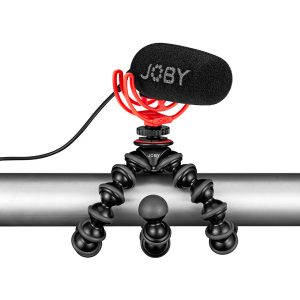Joby Wavo Shotgun - Mikrofoni, jossa on musta vaahtomuovisuojus, on asennettu taipuisalle jalustalle, jossa on taivutettavat jalat ja joka on kiedottu tukevasti metallitangon ympärille.