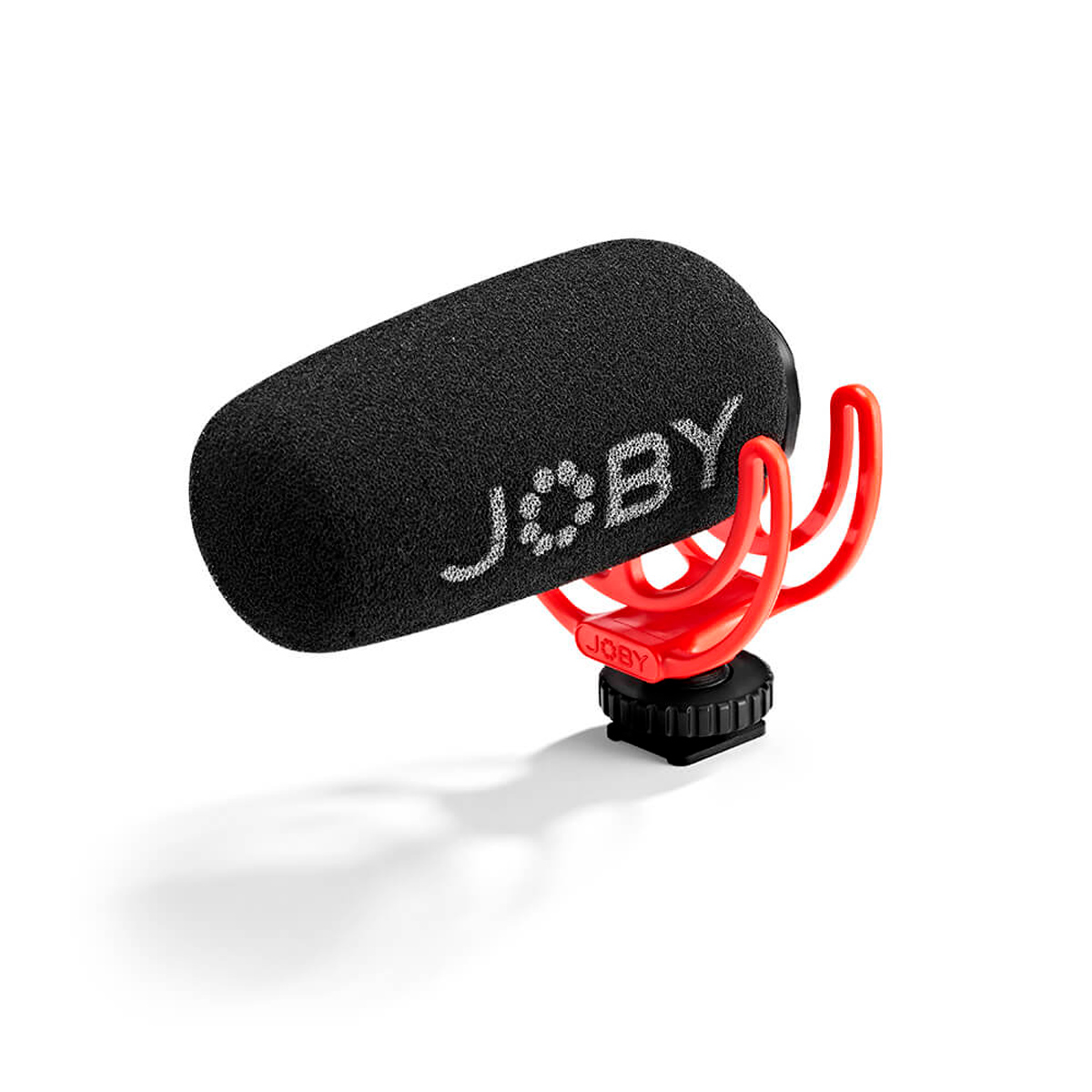 Joby Wavo Shotgun - Mikrofoni on kompakti mikrofoni mustalla vaahtomuovisella tuulisuojalla ja punaisella iskukiinnityksellä, joka on suunniteltu kameroihin tai mobiililaitteisiin, kuvassa valkoista taustaa vasten.