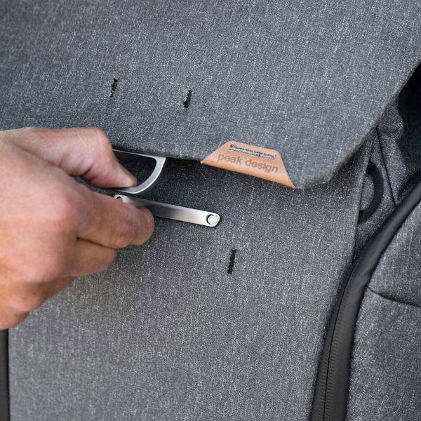 Käsi säätää tummanharmaa Peak Design Everyday Backpack v2 30L -kamerareppu metallisalpaa, joka kiinnittää läpän kiinni.