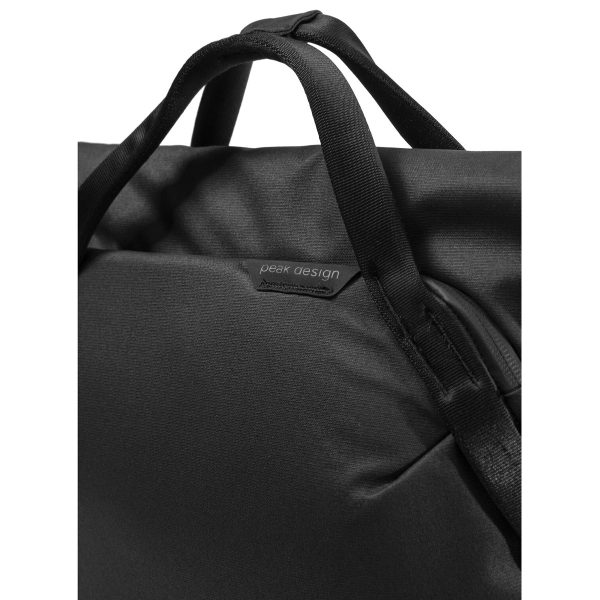 Lähikuvassa Peak Design Everyday Totepack 20L v2 mustassa värissä, jossa korostuvat sen kestävä kangas, pehmustetut kahvat ja Peak Designin logomerkki yläosan lähellä.
