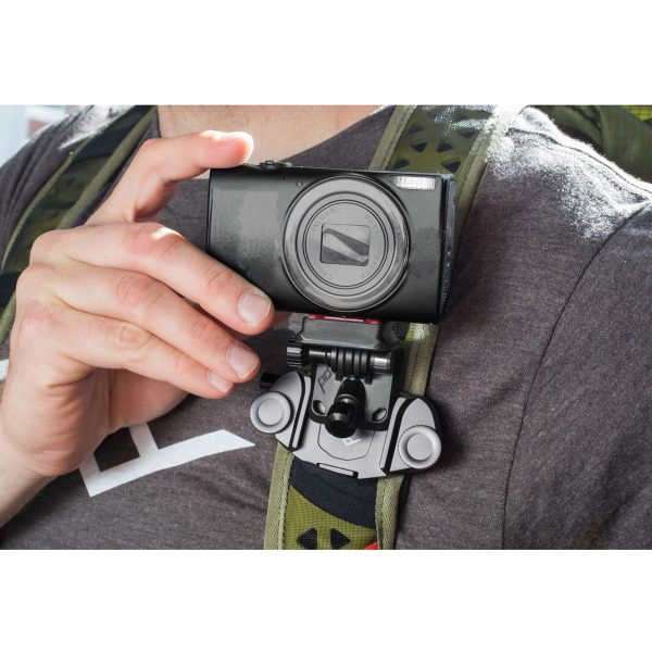 Harmaaseen paitaan ja reppuun pukeutunut henkilö pitää mustaa kameraa, joka on kiinnitetty reppuhihnaan Peak Design POV Kit for Capture -laitteella.