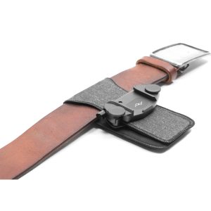 The Peak Design ProPad V2 is a brown leather belt with grey fabric and a black plastic clip, designed to securely hold camera-like objects on your belt.