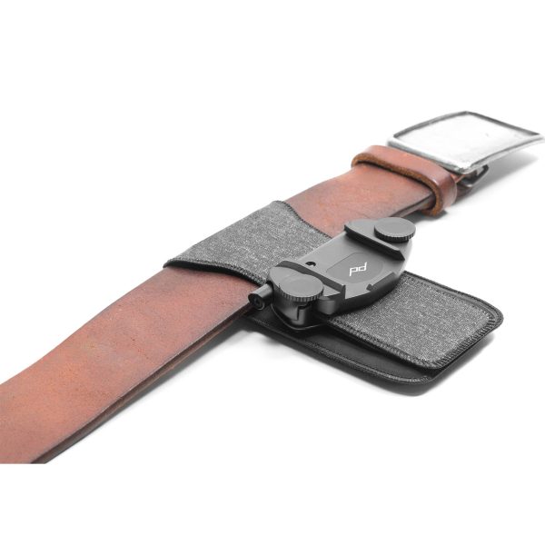 The Peak Design ProPad V2 is a brown leather belt with grey fabric and a black plastic clip, designed to securely hold camera-like objects on your belt.
