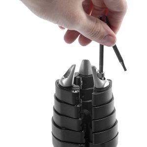 Käsi käyttää Peak Design Spike Feet Set -työkalua ruuvin säätämiseen mustassa, segmentoidussa laitteessa, jossa on metalliset kärjet.