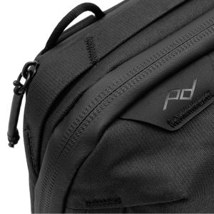 Lähikuva Peak Design Tech Pouch - Black -laukusta, jossa näkyy vetoketju vetokielekkeellä, pieni pd-logolla varustettu lappu sekä näkyvä kankaan rakenne ja ompeleiden yksityiskohdat.
