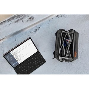 Tabletti, jossa on näppäimistö ja jossa näkyy viestisovellus, istuu betonilla avoimen mustan Peak Design Tech Pouch -laukun vieressä, jossa on johtoja, kyniä ja elektroniikkaa.