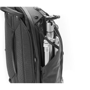 Peak Design Travel Backpack 45L -kamerareppu, musta, sisältää vetoketjullisen sivutaskun, johon mahtuu kokoontaitettu hopeinen kolmijalka, mikä osoittaa sen kapasiteetin valokuvausvälineiden kuljettamiseen.