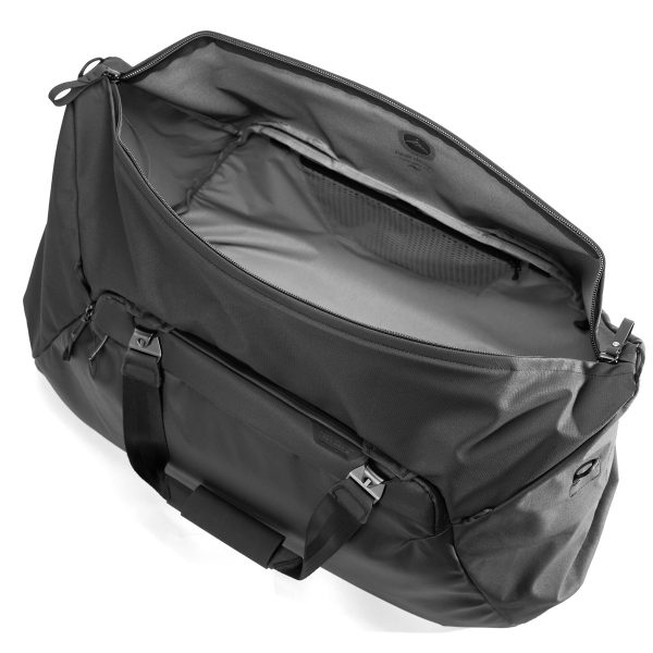 Peak Design Travel Duffel 65L - Black on esitetty avattuna ylhäältä päin, jolloin sen tilava päälokero ja vetoketjullinen verkkotasku ovat näkyvissä. Laukussa on tukevat kahvat ja tyylikäs, moderni muotoilu.