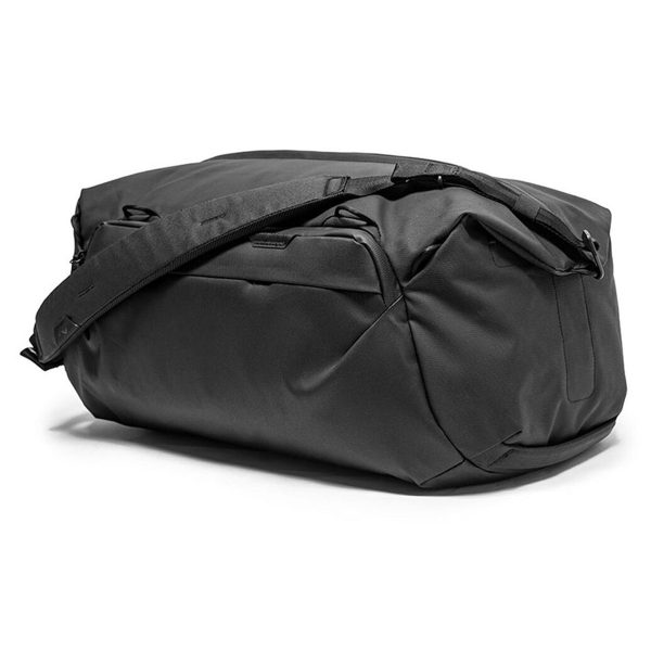 Peak Design Travel Duffel 65L - Black näkyy valkoisella pohjalla, ja siinä on tyylikäs minimalistinen muotoilu, useita vetoketjulokeroita ja kätevä olkahihna.