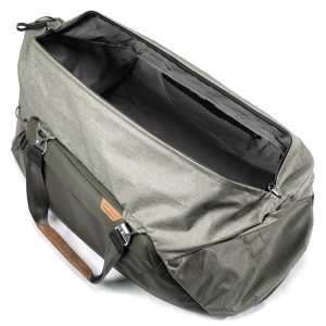 Peak Design Travel Duffel 65L - Sage on tilava, avoin harmaan ja vihreän värinen laukku, jossa on mustat hihnat, ruskea nahkakahva-aksentti ja tyhjä päälokero kuvattuna ylhäältä katsottuna.