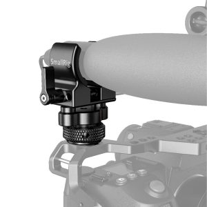 Lähikuva SmallRig 2352 Shotgun Mic Holder (Cold Shoe) -mikrofonipidikkeestä, joka on asennettu kameran häkkiin, jossa on nuppi ja joka on suunniteltu kiinnittämään mikrofonit tukevasti kameran kahvaan.