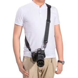 The subject is wearing a white short-sleeved polo shirt and beige trousers, and a black camera hangs from his shoulder to his hip via a SmallRig 2428 Camera Shoulder Strap. His left arm rests next to him.