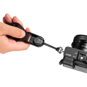 The hand attaches the SmallRig 2428 Camera Shoulder Strap with a quick release buckle to a black Sony Alpha α6400 camera and shows a close-up of the strap's attachment mechanism.