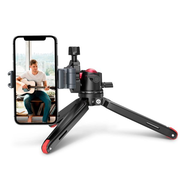 Mies soittaa akustista kitaraa älypuhelimella, joka on kiinnitetty SmallRig 2664 Tabletop Minitripod with Panoramic Ballhead -laitteeseen, ja hänen takanaan olevasta ikkunasta näkyy kaupunkinäkymä.