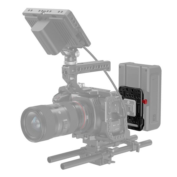 Ammattikäyttöön tarkoitettu videokamerakalusto, jonka päällä on ulkoinen näyttö ja sivulle asennettu suuri akku, ja jossa on musta SmallRig 2988 Battery Plate V-Mount -akkujalusta, jossa on punainen vapautussalpa; kaikki muut varusteet on esitetty harmaalla.