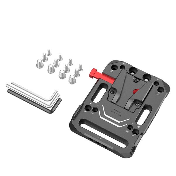 Mustaa ja punaista metallia oleva SmallRig 2988 Battery Plate V-Mount -paristokilpi on kuvassa, jossa on useita kiinnitysreikiä, neljä L-kirjaimen muotoista kuusiokoloavainta ja kymmenen hopeista ruuvia, jotka on sijoitettu sen viereen valkoiselle taustalle.