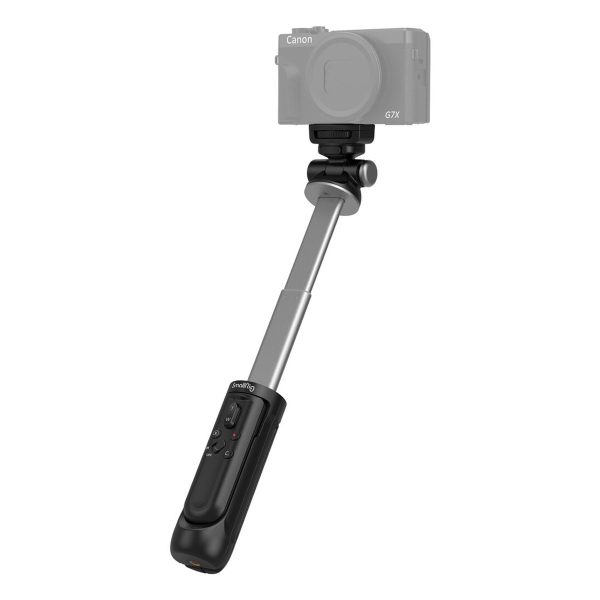 SmallRig 3326 SR-RG1 Wireless Shooting Grip mustaa ja hopeaa, joka on kuvassa laajennettuna käsikäyttöisenä selfie stick -jalustana kaukosäätimellä, pitää puoliksi läpinäkyvää Canon G7X -digitaalikameraa.