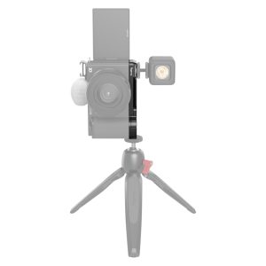 Edestä katsottuna SmallRig 3523 Extension Grip for Sony ZV-E10, musta, kiinnitettynä pienellä jalustalla, ulkoinen valo kameran sivulla ja pystysuoraan asetettu kääntyvä näyttö; kamera ja jalusta näkyvät puoliksi läpinäkyvinä.