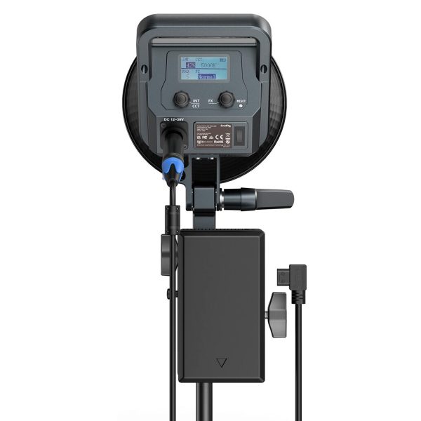 Kuvassa on SmallRig 3676 RA V1 V-Mount -akkulevyn takanäkymä, joka on kiinnitetty jalustalle asennettuun LED-studiovalaisimeen ja jossa on näkyvissä digitaalinen näyttö, ohjauspainikkeet, nupit ja liitetyt virtajohdot.