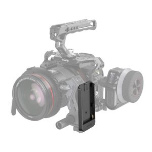 SmallRig 3777 L-sarjan akkulevy on näkyvästi esillä etualalla, ja se näyttää terävältä ja yksityiskohtaiselta, kun taas sen takana oleva ammattikäyttöön tarkoitettu videokamera on osittain läpinäkyvä ja epätarkka.