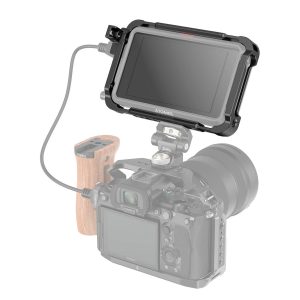 Musta SmallRig 3788 Cage Kit for Atomos Ninja V/V+, jossa on liitetty kaapeli, on asennettu digitaalikameran päälle, jonka toisella puolella on puinen kahva; kameran runko on osittain läpinäkyvä.