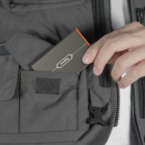 Hand put the SmallRig 4107 Memory Card Case for Sony CFexpress Type A in the zipped pocket of the grey jacket.