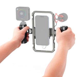 Henkilö pitää SmallRig 4121 All-In-One Video Kit Mobile Basic -videokojetta molemmilla käsillään, ja siinä on keskellä kiinnitetty älypuhelin, vasemmalla pieni kamera ja oikealla ulkoinen mikrofoni.