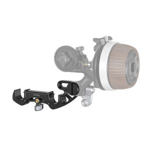 SmallRig 4151 15 mm:n sauvakiinnike, joka on kompakti musta metallinen lisävaruste, jossa on kiinnitysnuppi, on tarkennettuna, kun taas kameran seurantatarkennusjärjestelmä, jossa on puukuvioitu nuppi, näkyy taustalla epäselvänä.
