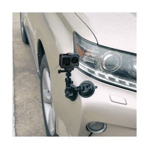 SmallRig 4119 Cage for DJI Osmo Action 3 / 4 on kiinnitetty beigen auton kylkeen etupyörän ja ajovalojen lähelle mustalla imukuppikiinnikkeellä. Auto on pysäköity päällystetylle pinnalle.