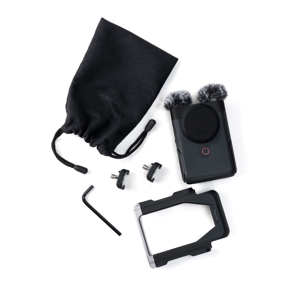 The Canon PowerShot V10 Advanced Kit silver compact camera includes a black drawstring bag, a handheld audio recorder with two hairy windscreens, a metal L-shaped tool, two small adapters and a removable black mount with a white background.