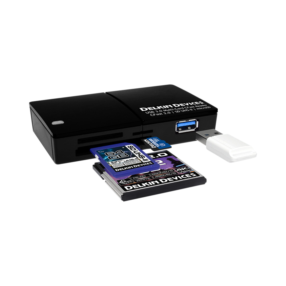 Musta DELKIN Cardreader CFast/SD/Micro UHS-II (USB 3.0), jossa on useita korttipaikkoja, näkyy valkoisella taustalla, ja siinä on useita osittain asetettuja muistikortteja ja sen vieressä USB-suojakorkki.