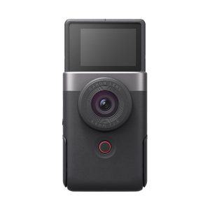 The Canon PowerShot V10 silver compact camera is a black digital camera with a large circular lens, a red button below the lens and a forward-facing LCD screen at the top.