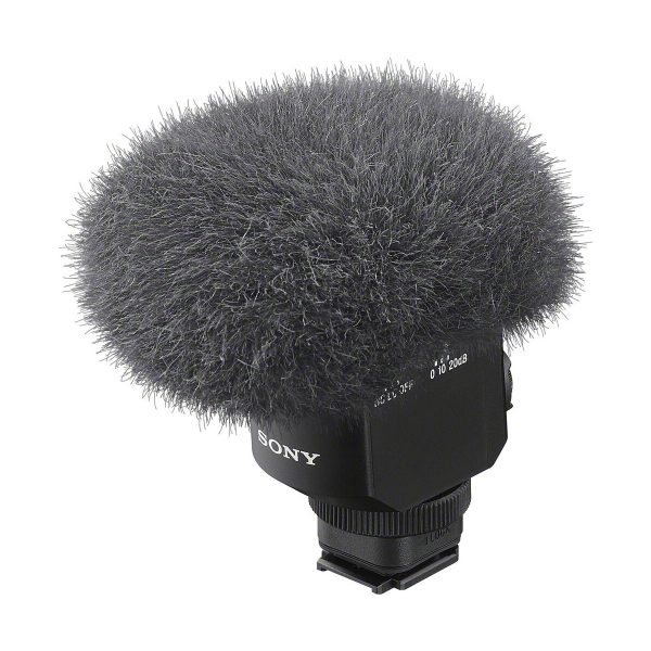sony_ecm_m1_03 Lähikuva Sony ECM-M1 -mikrofonista, jossa on pörröinen harmaa tuulisuoja, joka vähentää tuulen aiheuttamaa melua äänitallennuksen aikana, ja musta pohja, jossa on selvästi merkityt säätimet.