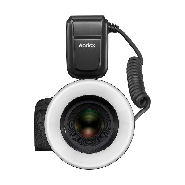 Mustan värinen Godox MF-R76C TTL Macro Ring Flash - Canon on kiinnitetty kameran objektiivin etupuolelle ylhäältä kuvattuna. Pyöreä salama ympäröi objektiivia, ja sen virtalähde on kytketty sen päällä olevalla kierrekaapelilla.
