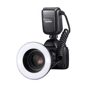 Digitaalikamera, jossa on Godox MF-R76C TTL Macro Ring Flash for Canon ja ulkoinen Godox AD300 Pro -salamalaite, joka on kytketty toisiinsa kierrekaapelilla, on kuvattu valkoista taustaa vasten.